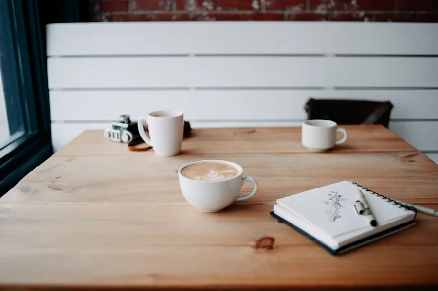 Two coffee cups and an open sketch notebook on a warm wooden table